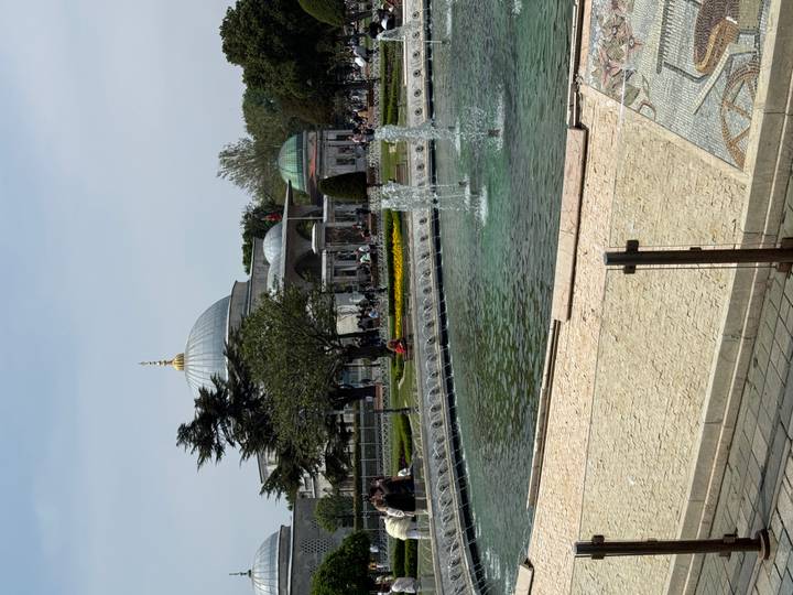 Low fountain pool and garden with domed Ottoman building in the background.
