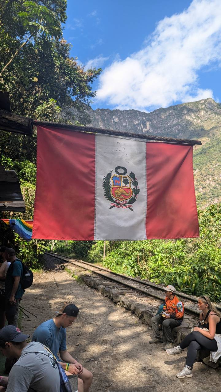 Close-up of the Peruvian national flag hanging between lush green forested hills.