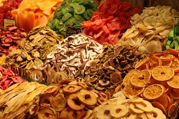 Colorful heap of assorted dried fruits and nuts displayed at a bustling market stall.