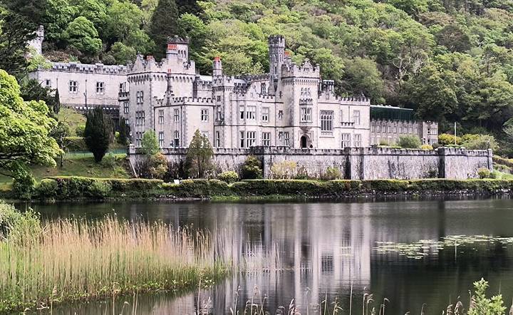 Kylemore Abbey reflected in still lake amid lush Connemara greenery.