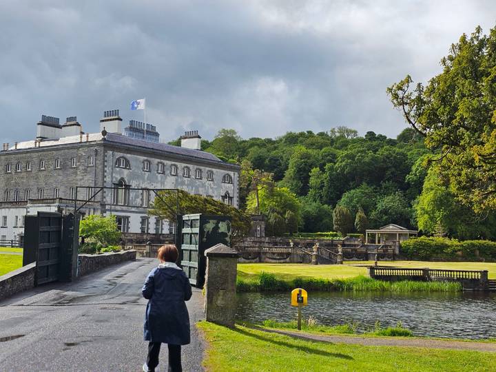 Visitor walking toward Westport House estate gardens and lake on overcast day.