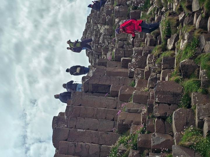 Visitors climbing the hexagonal basalt columns at Giant’s Causeway.