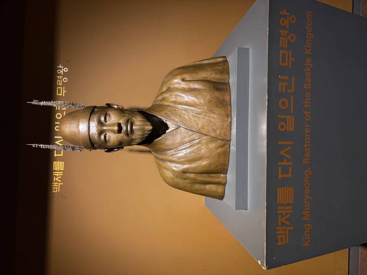 Bronze bust of King Muryeong displayed in a museum with Korean and English captions.