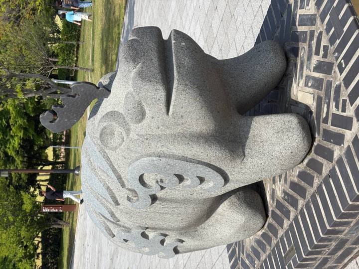 Close-up of a decorative stone animal statue in a park setting.
