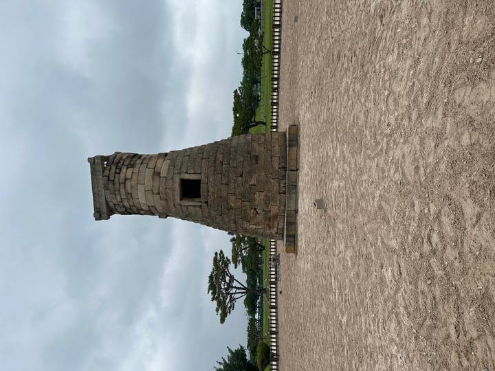 Stone Cheomseongdae astronomical observatory standing alone on a gravel yard under a gray sky.