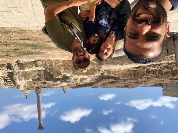 Family selfie with Pompey’s Pillar and blue sky in the background, child in front