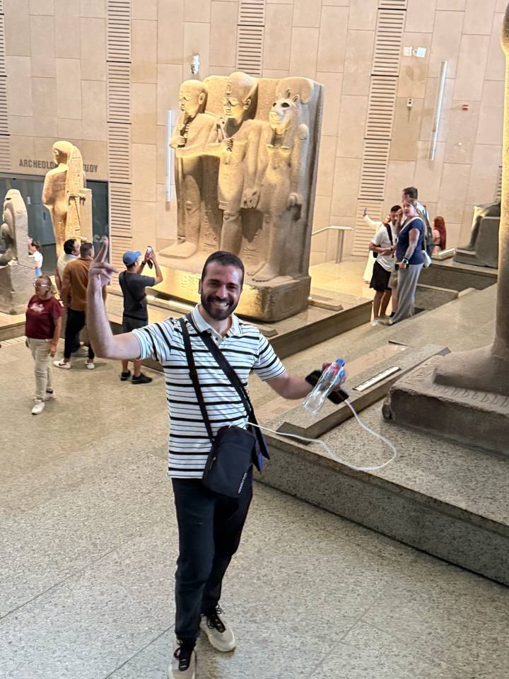 Tour guide celebrating inside the Egyptian Museum with statues and tourists around