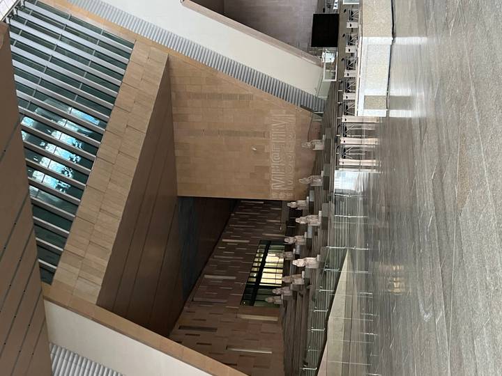 Modern atrium of the Grand Egyptian Museum featuring rows of seated statues on terraced steps.