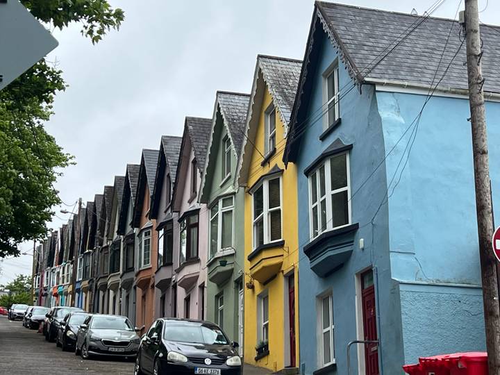 Row of narrow colourful terraced houses along a street on an overcast day