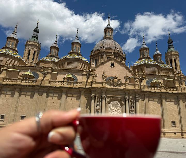 Blurred hand holding a coffee cup with ornate basilica domes in the background