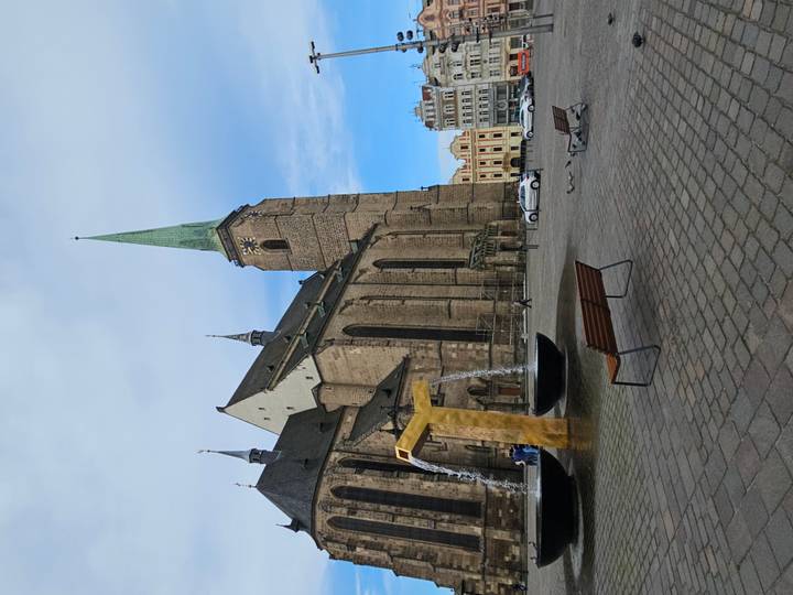 Gothic cathedral and modern fountain in spacious square on a clear day.