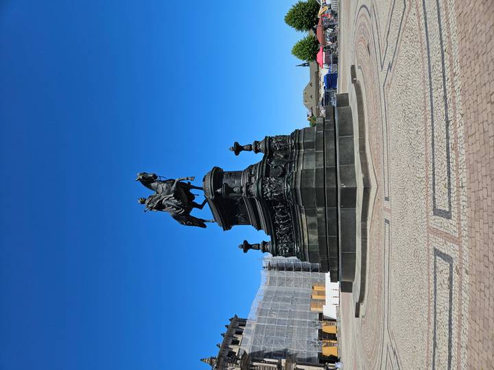 Equestrian monument standing alone in sunny plaza under cloudless blue sky.