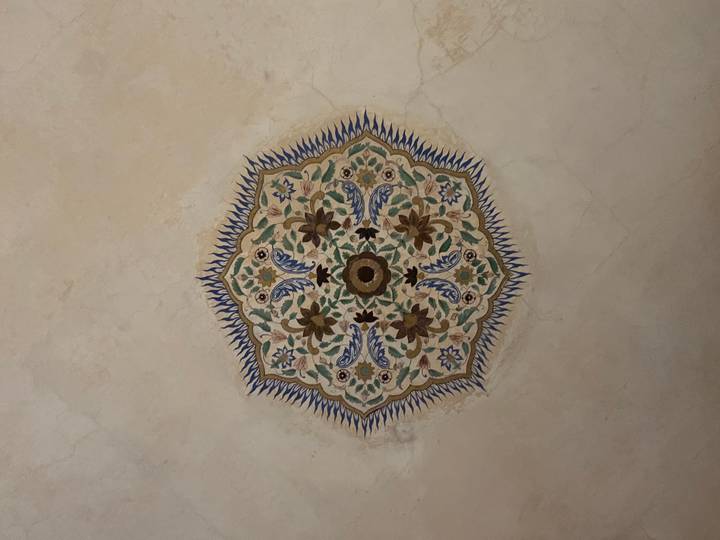 Intricate floral mandala painting decorating the ceiling of a historic Indian palace room.