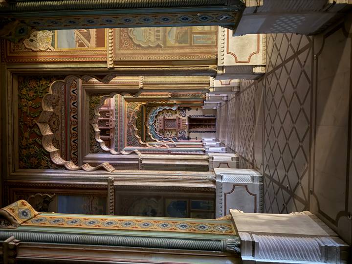 Long ornate corridor of colourful arches and frescoes leading to a distant doorway inside Patrika Gate.