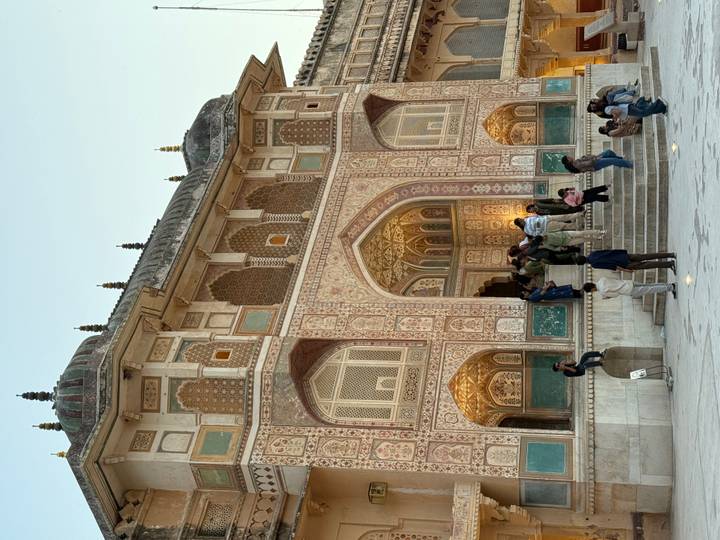 Visitors congregate at the richly inlaid Ganesh Pol gate of Amber Fort during golden evening light.