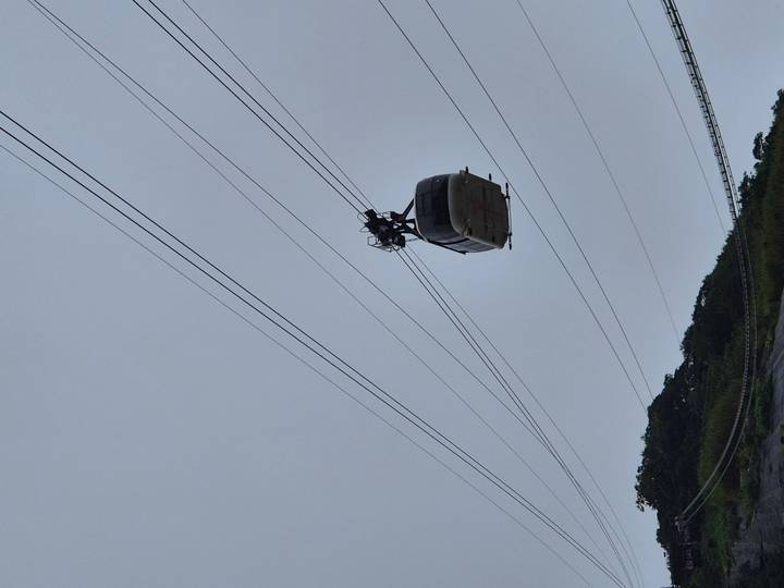 Cable car suspended high on wires against an overcast sky, likely en route to Sugarloaf Mountain