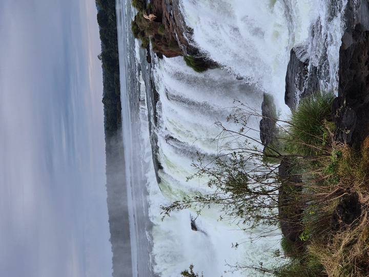 Powerful Iguazu Falls thundering over a rocky cliff with mist rising into the sky