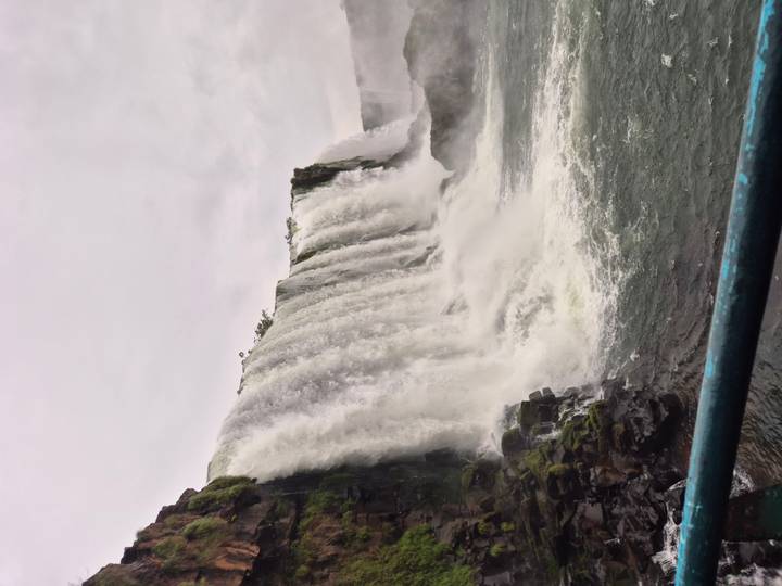 Side view of cascading Iguazu Falls plunging into the river below on a grey day