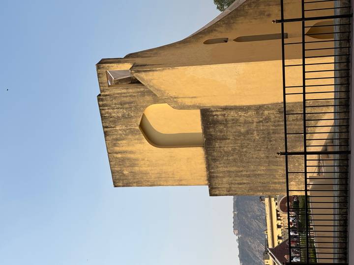 Simple yellow observational structure of Jaipur’s Jantar Mantar against a clear blue sky