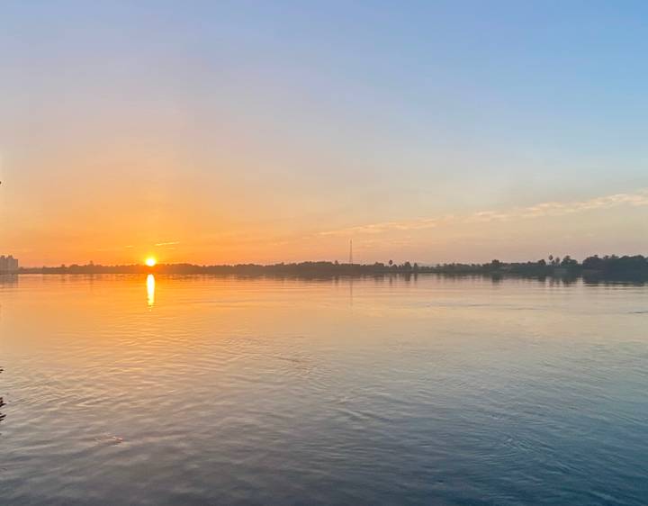 Soft sunrise over a wide calm river reflecting golden light on the water