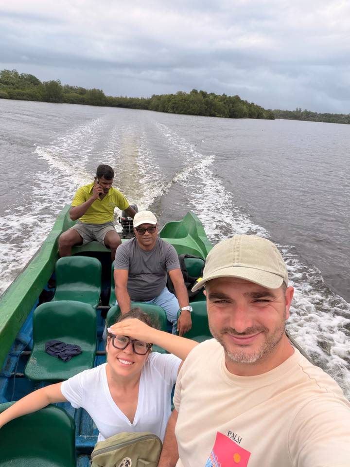 Casual selfie on a small green motorboat speeding across brown river water.