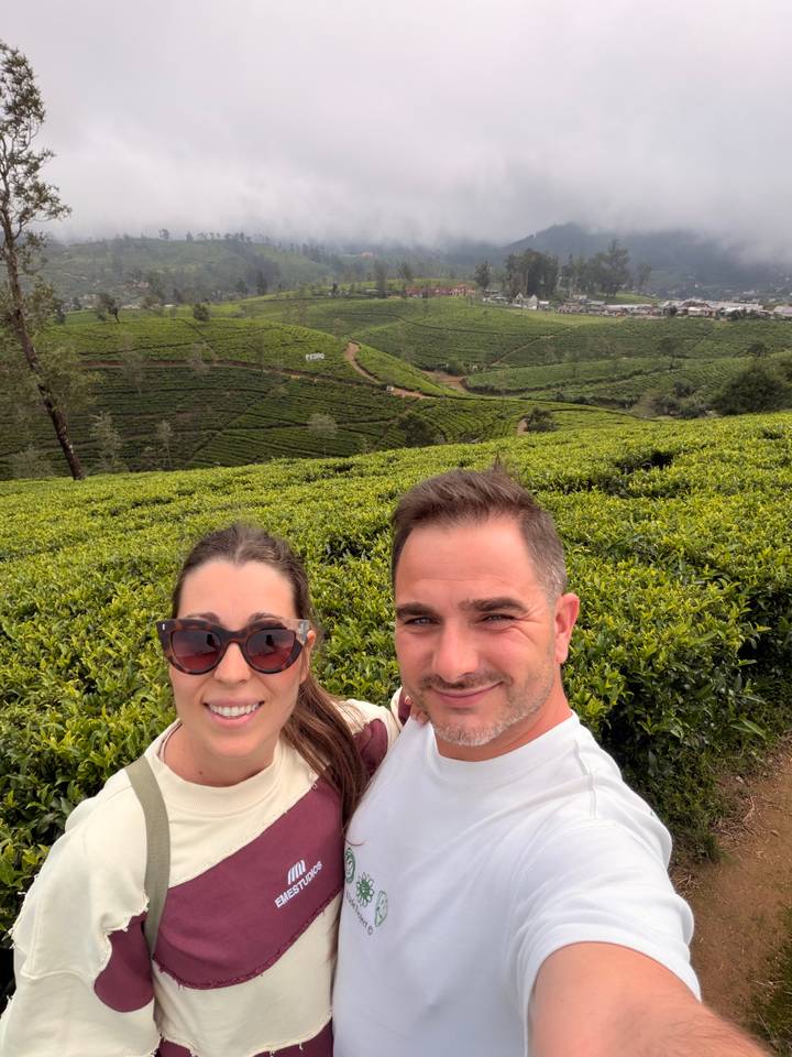 Selfie of couple amid rolling green tea plantations stretching over the hills.