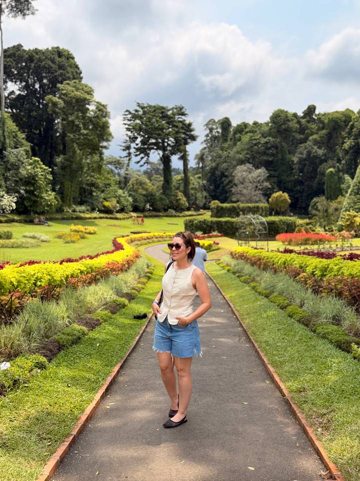 Woman enjoys colourful landscaped paths and flower beds in a lush botanical garden.