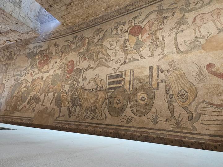 Overhead perspective of intricate Roman mosaic depicting chariots and hunters on a villa floor.