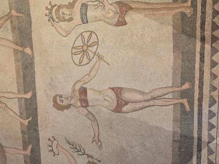 Ancient Roman mosaic depicting a young woman holding a disc, known from the Bikini Girls series.