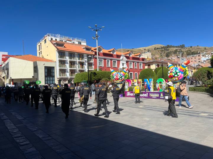 Police officers and parade participants walk through Puno’s main square with colorful balloons and signage