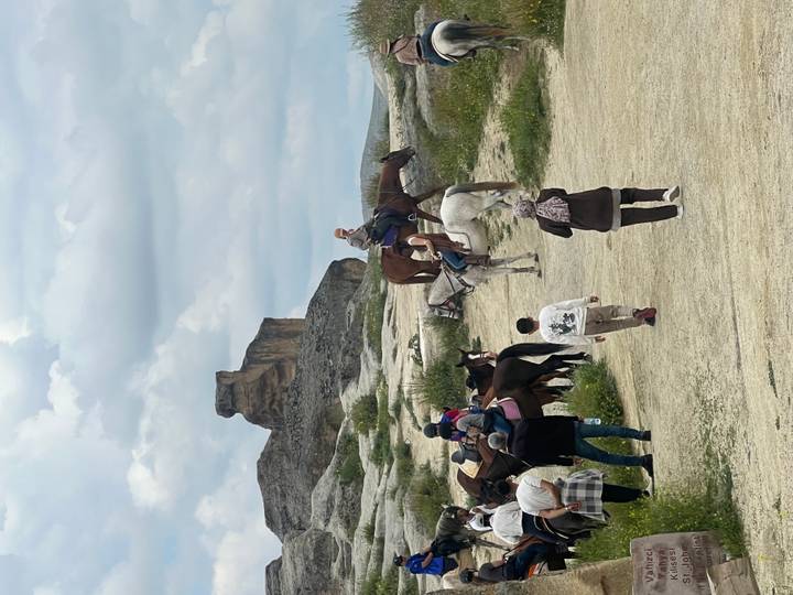 Tourists mount horses amid Cappadocia’s rolling hills and unique rock outcrops.