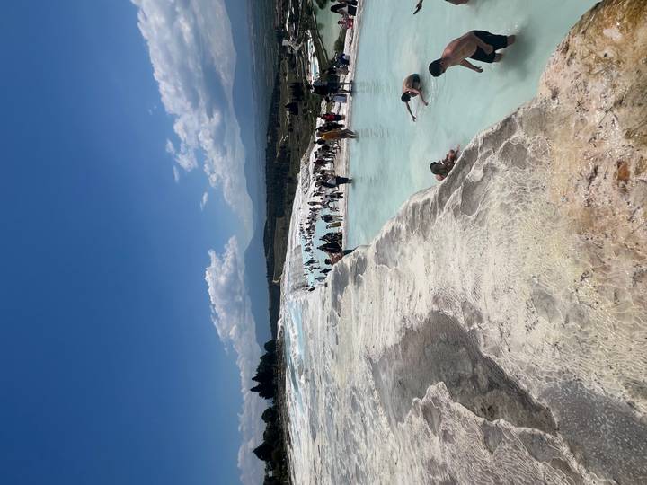 Glittering blue thermal pools cascade down the white travertine terraces of Pamukkale.
