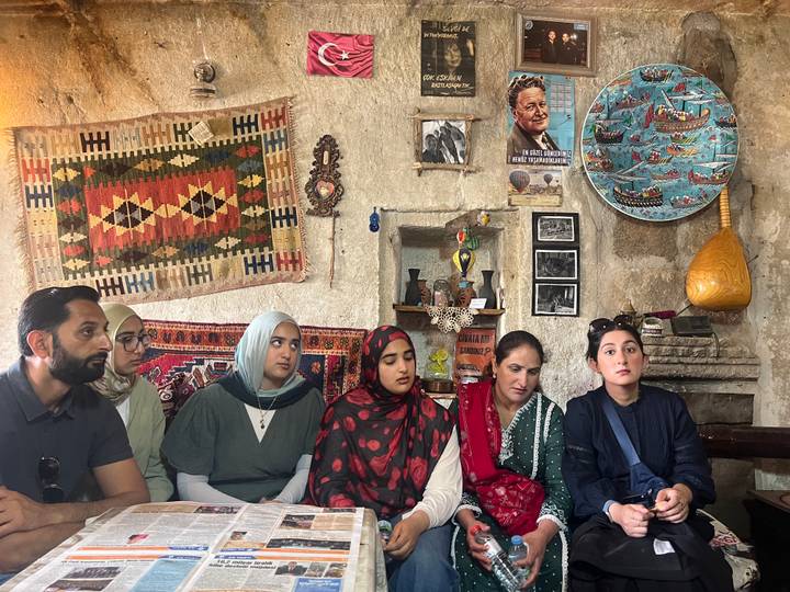 Small group listens attentively inside a traditional Cappadocian cave house decorated with crafts.