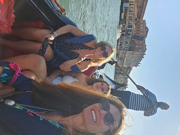 Tourists enjoy a gondola ride along Venice’s Grand Canal with a striped-shirt gondolier.