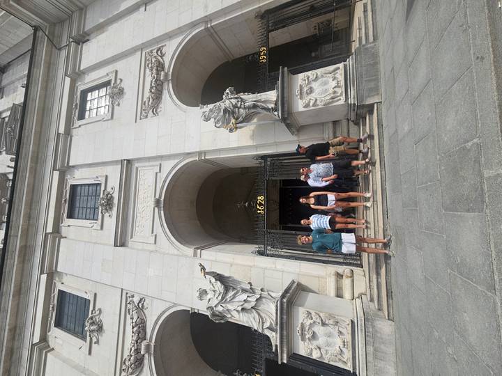Travelers exit a grand stone church façade adorned with statues and baroque details.