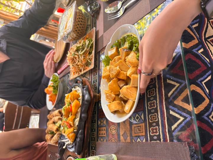 A colourful Vietnamese meal with tofu, salads and sizzling dishes served on patterned tablecloths.