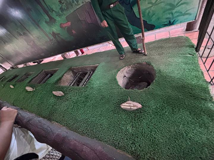 A demonstration pit lined with artificial grass shows traps used in the Cu Chi tunnels exhibit.