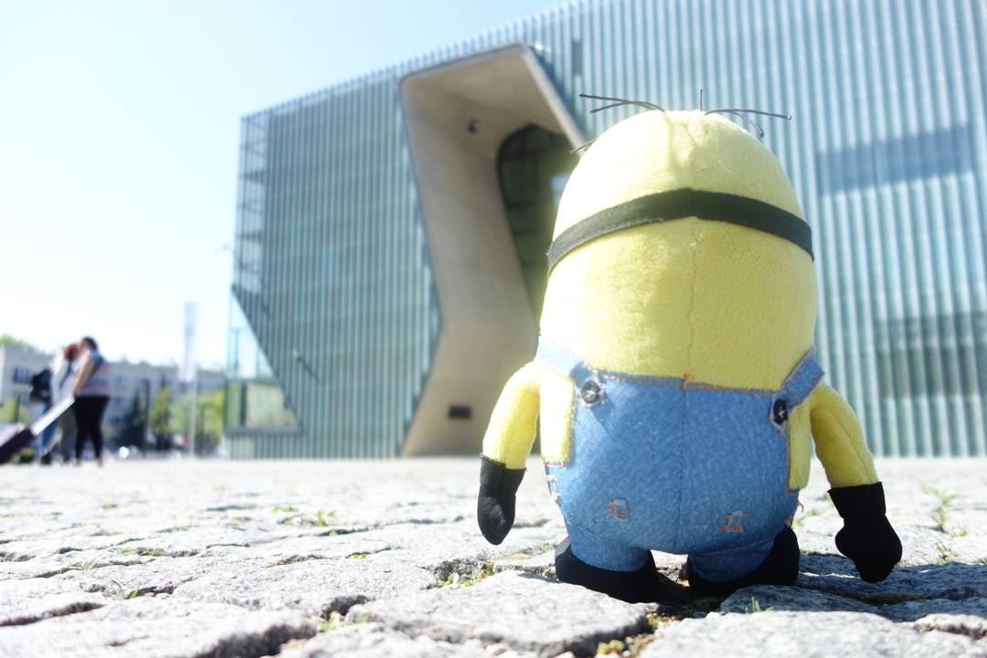 Peluche de personnage surplombant un bâtiment d'architecture moderne.