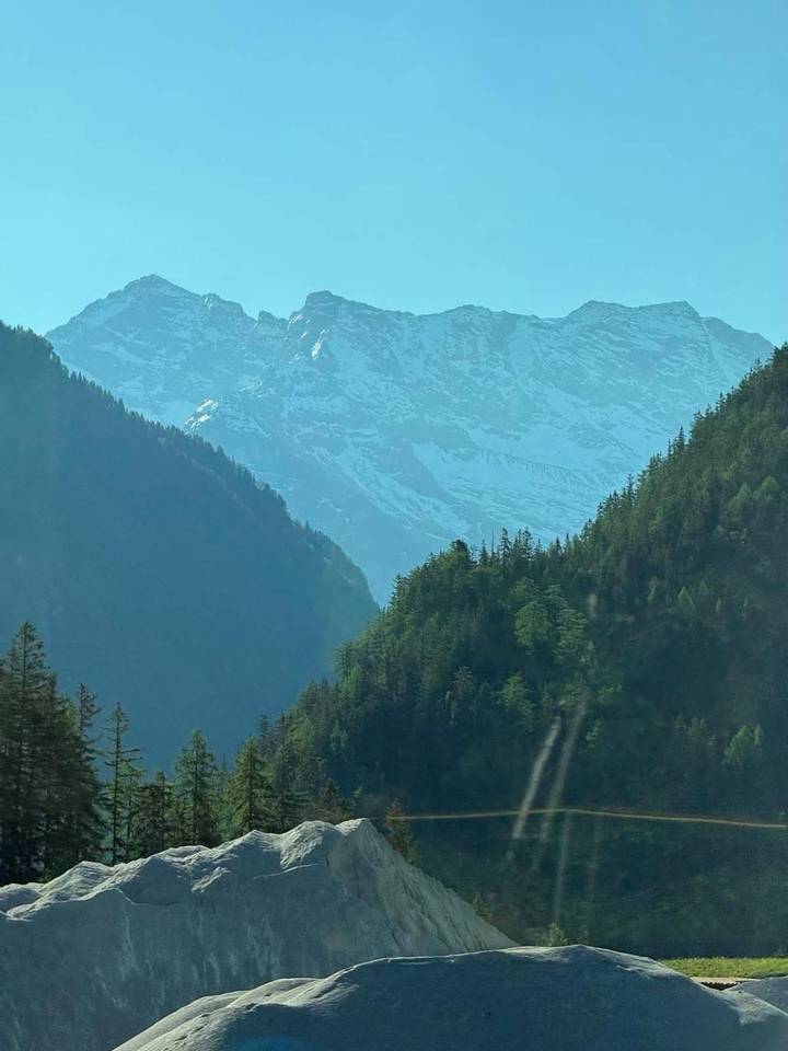 Snow-capped rugged mountain range with dense green forests below