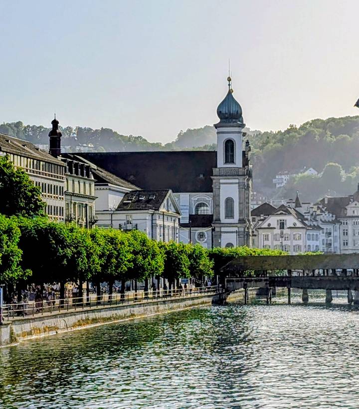 Riverfront scene of Lucerne with Jesuit Church and tree-lined promenade