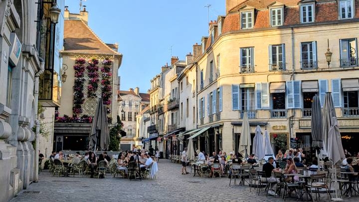 Bustling café-lined square with diners enjoying evening light in Dijon