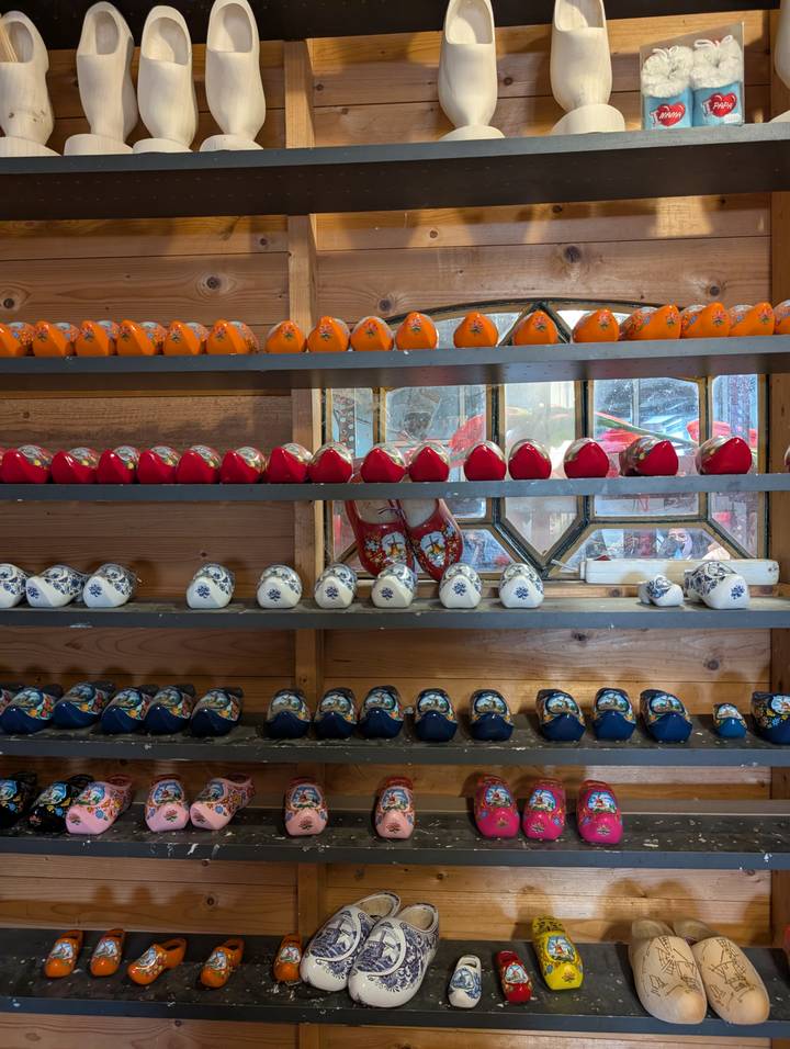 Rows of miniature ceramic clogs in vibrant colors displayed on wooden shelves
