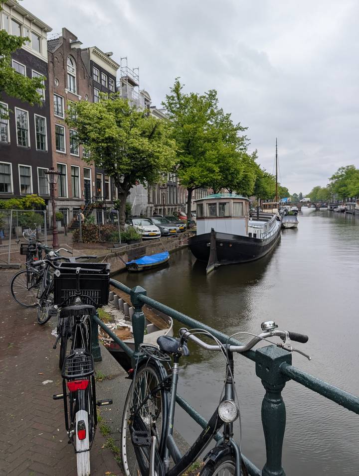 Houseboat and bicycles along calm canal under grey skies in Amsterdam