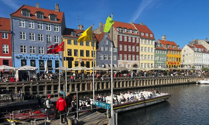 Colorful 17th-century houses along Copenhagen’s Nyhavn canal bustling with tour boats and cafés.