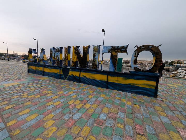Large metal letters spelling 'CAMINITO' stand on a painted cobblestone promenade in Buenos Aires’ La Boca district under an overcast sky.