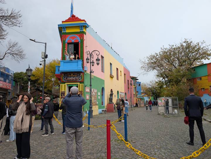 Color-blocked houses of La Boca line a pedestrian street as tourists stop to take photos of the colourful façades.