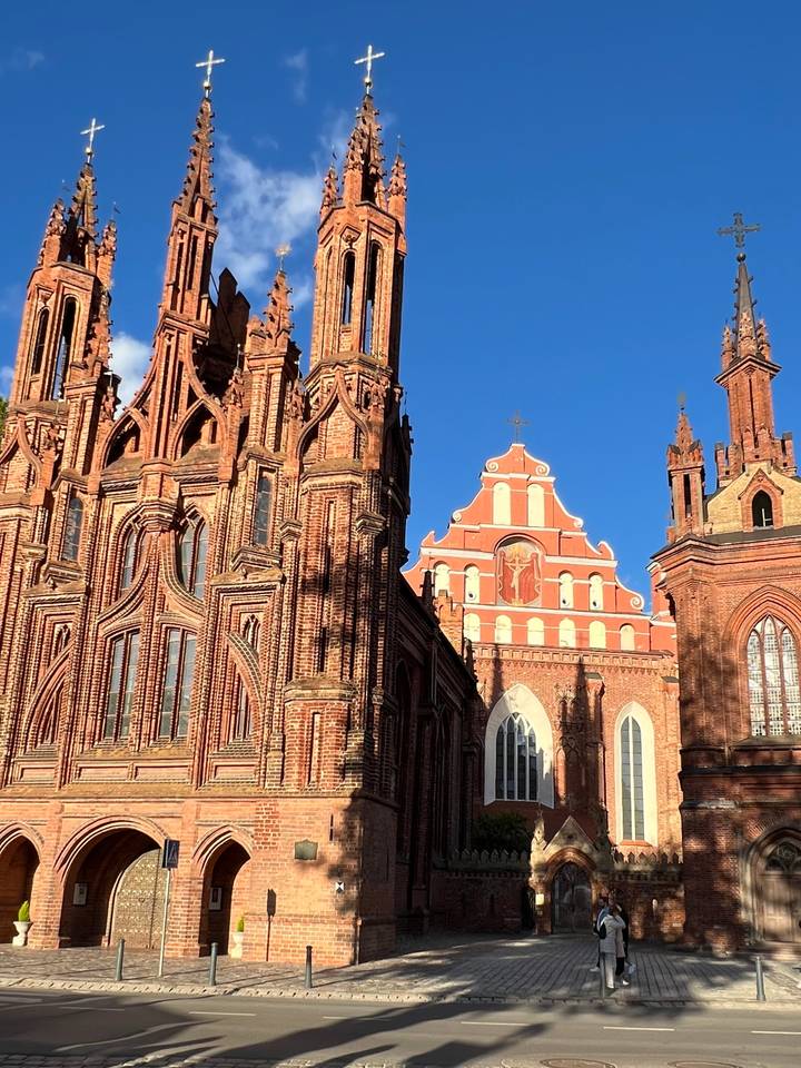 Detailed Gothic red-brick façade of St. Anne's Church in bright sunlight against blue sky.