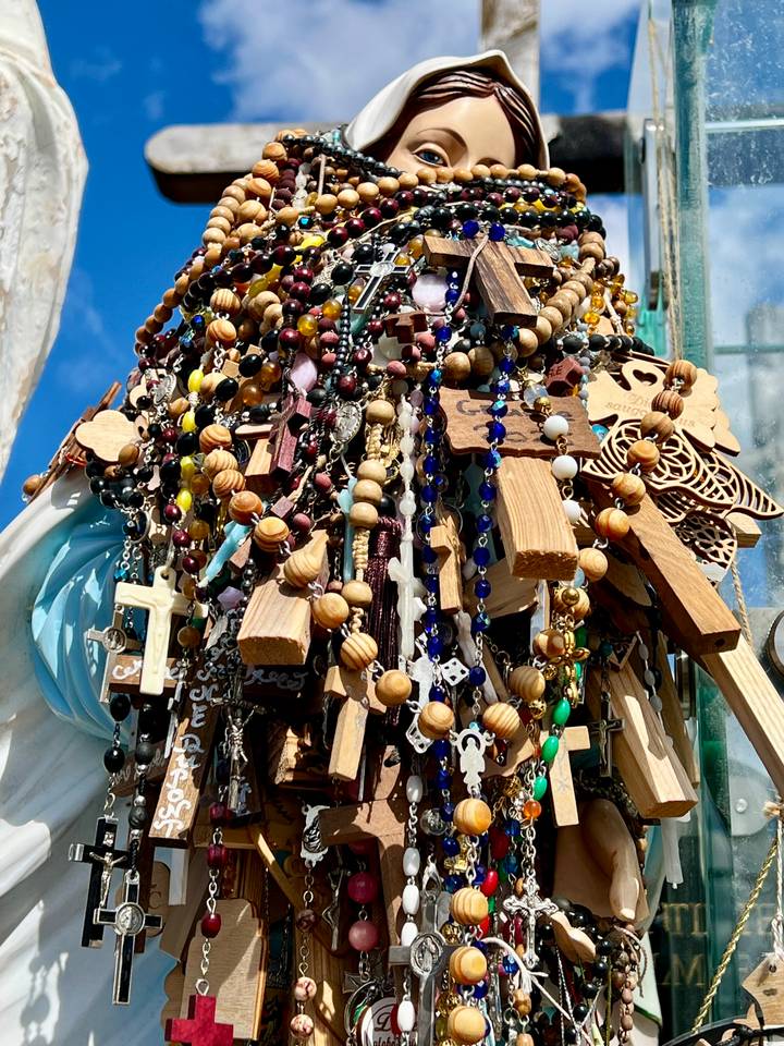 Close-up of a colourful cluster of wooden rosaries and trinkets hung together outdoors.