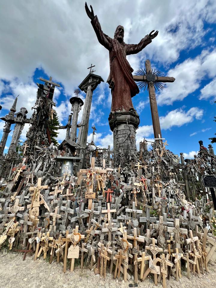 Dense field of thousands of wooden crosses and statues beneath a bright blue sky at the Hill of Crosses.