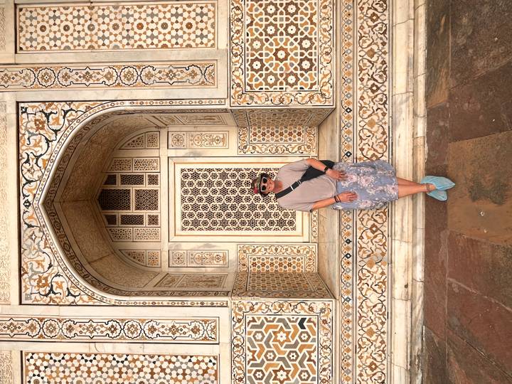 Traveler in front of intricately inlaid marble doorway at Itimad-ud-Daulah mausoleum in Agra.